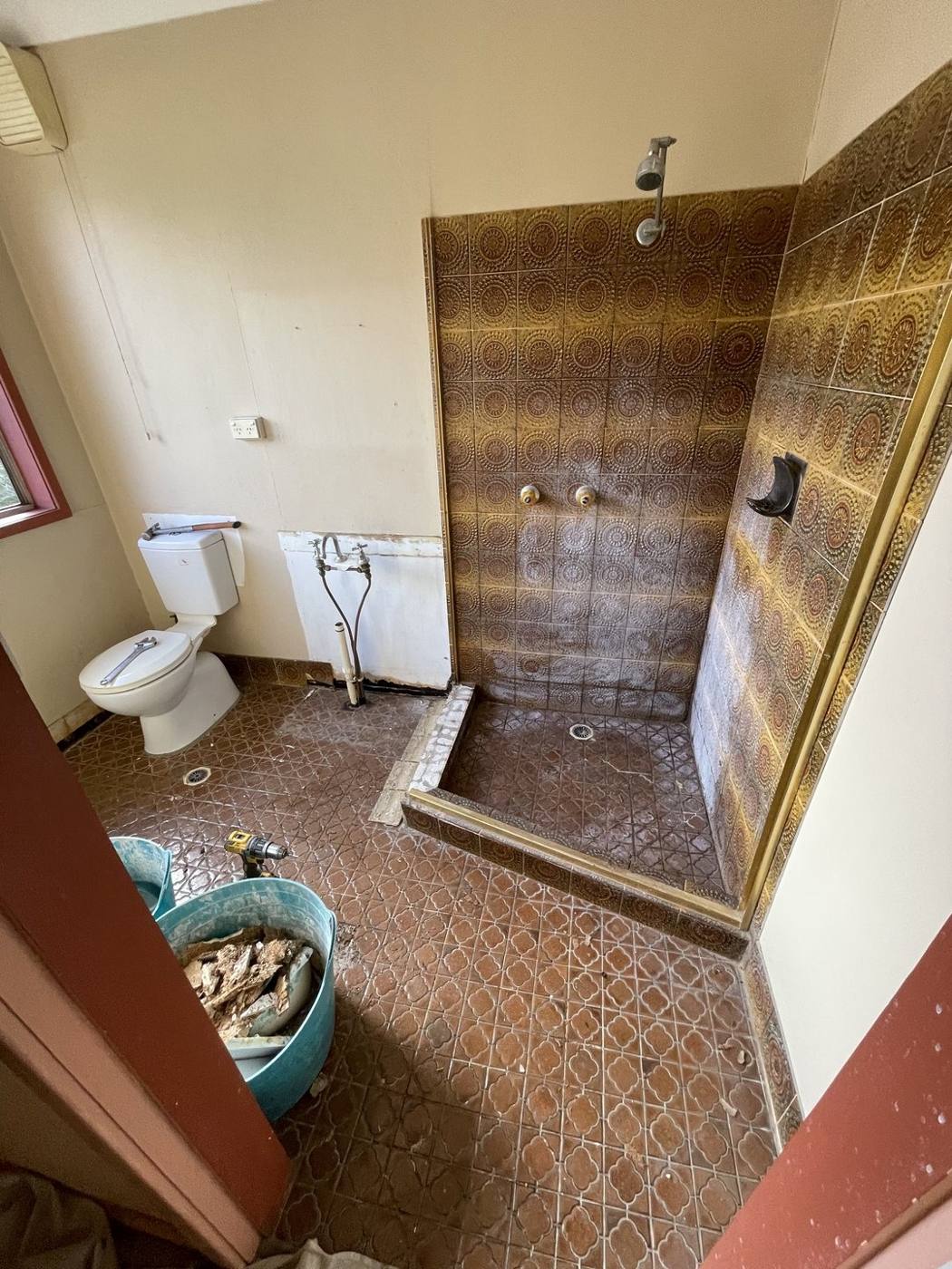Bathroom mid strip-out during renovation with rubble buckets, tools and tiles being removed, Baulkham Hills by Loel Homes
