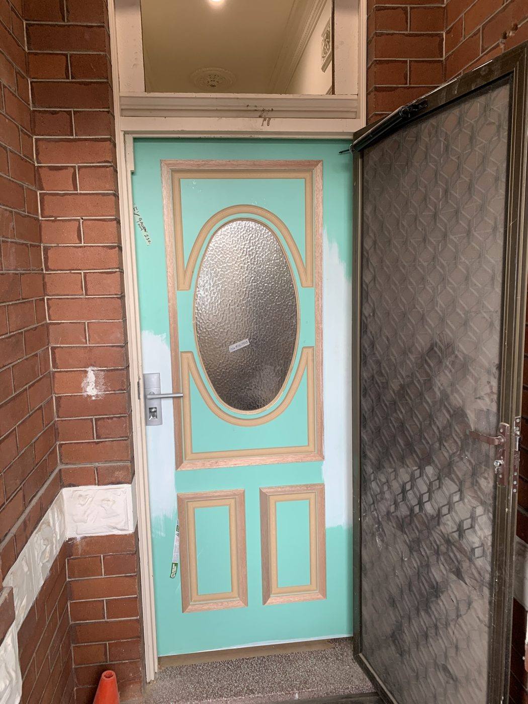 Same teal oval-glass front entry door viewed from the brick porch outside with the security screen open by Loel Homes