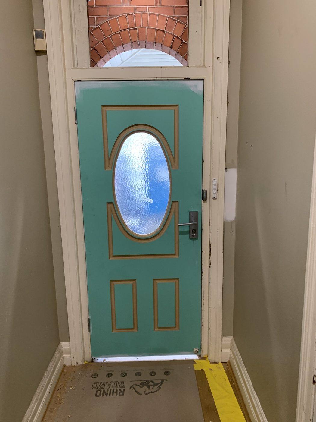 Teal front entry door with an oval frosted-glass insert and colonial panels, viewed from inside by Loel Homes