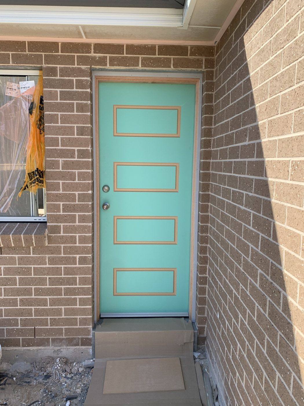 Teal five-panel colonial front entry door hung on a brick home by Loel Homes
