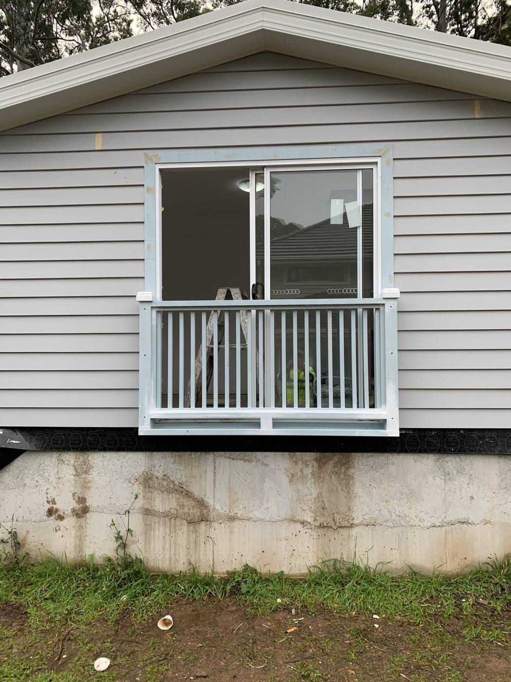 Aluminium handrail extension wrapping a Juliet balcony below a window on a weatherboard home by Loel Homes
