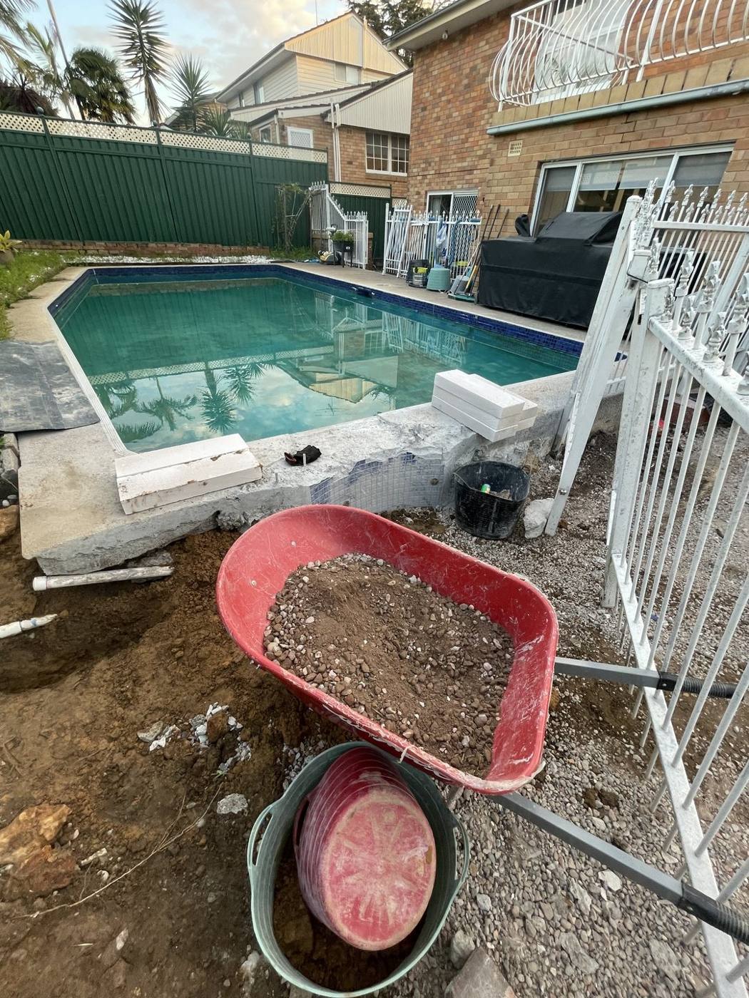 Old paver surround being demolished around an existing pool during a renovation by Loel Homes