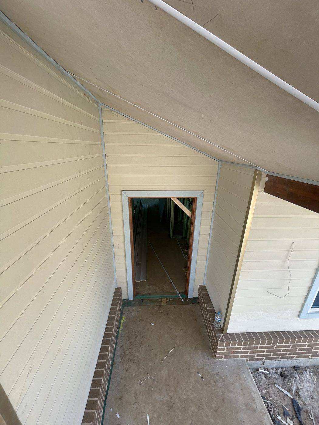Weatherboard cladding nearly complete around the entry with a timber feature post going up, rural home by Loel Homes