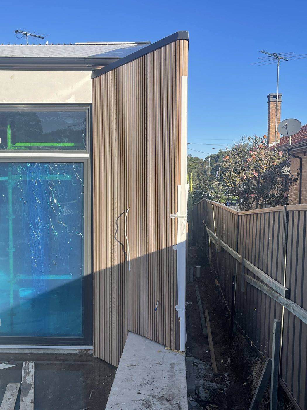 Pale vertical batten cladding running down a side elevation past a large window, duplex by Loel Homes